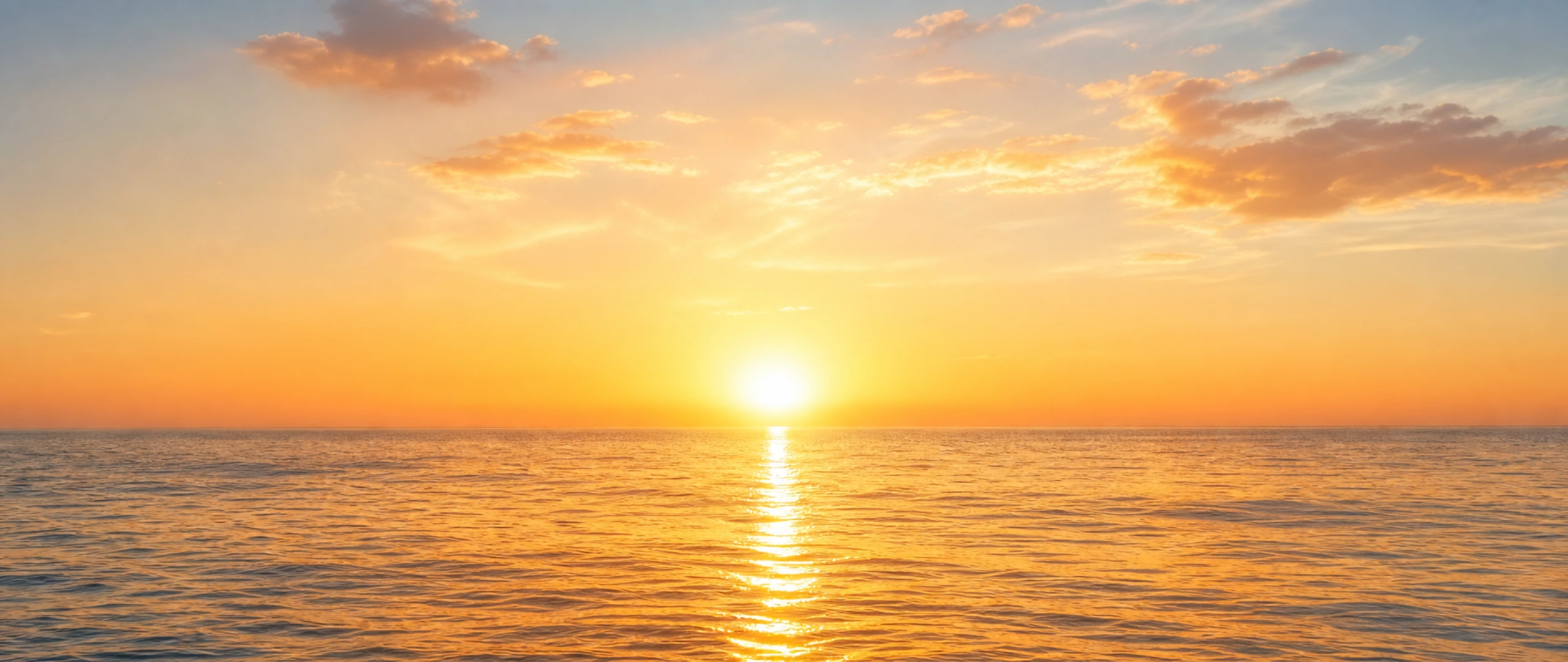 Sunrise spreading warm light across open water — a new day beginning